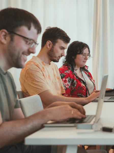 Drei Mandarinen sitzen nebeneinander vor ihren Labtops. 