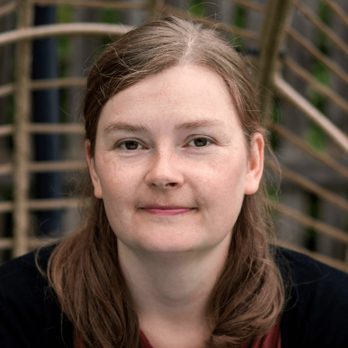 Lina hat langes dunkelblondes Haar und lächelt leicht.