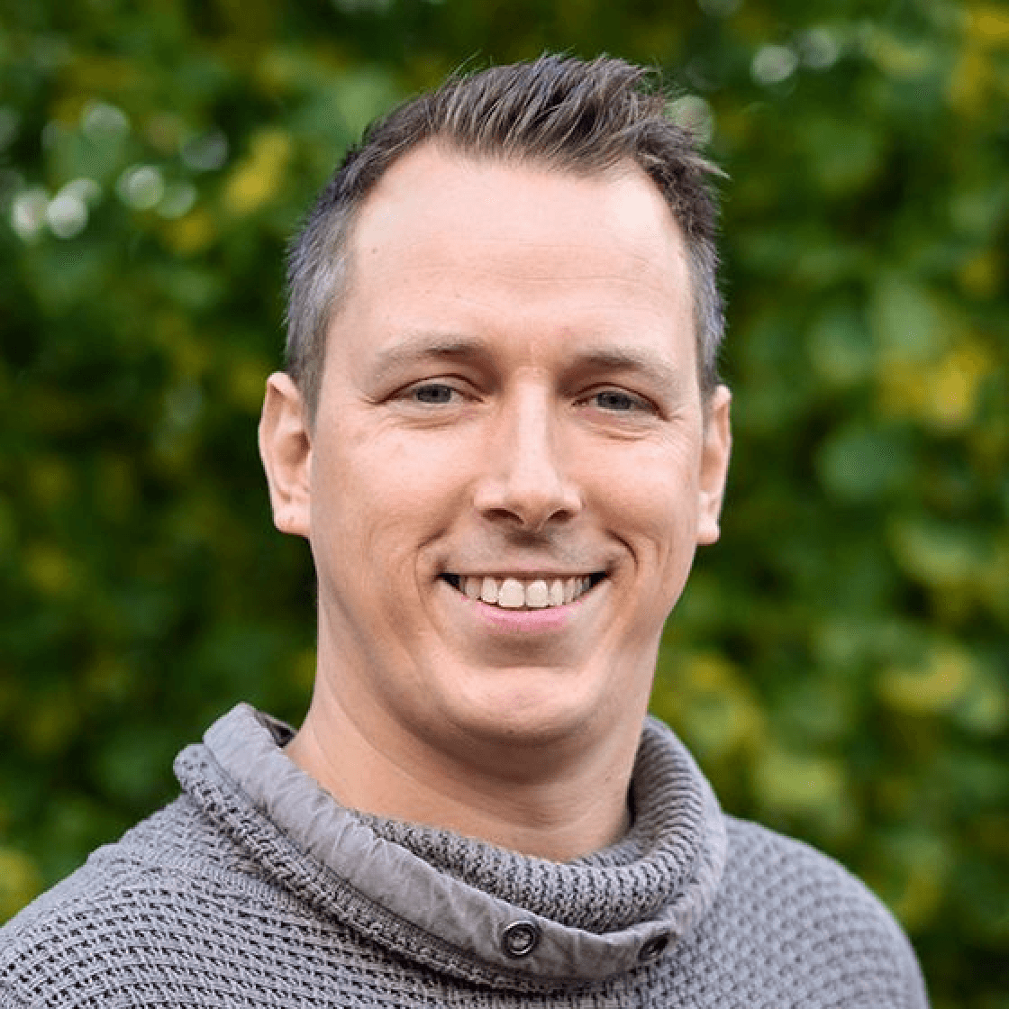 Marcel hat nach oben gegeltes Haar und lächelt.