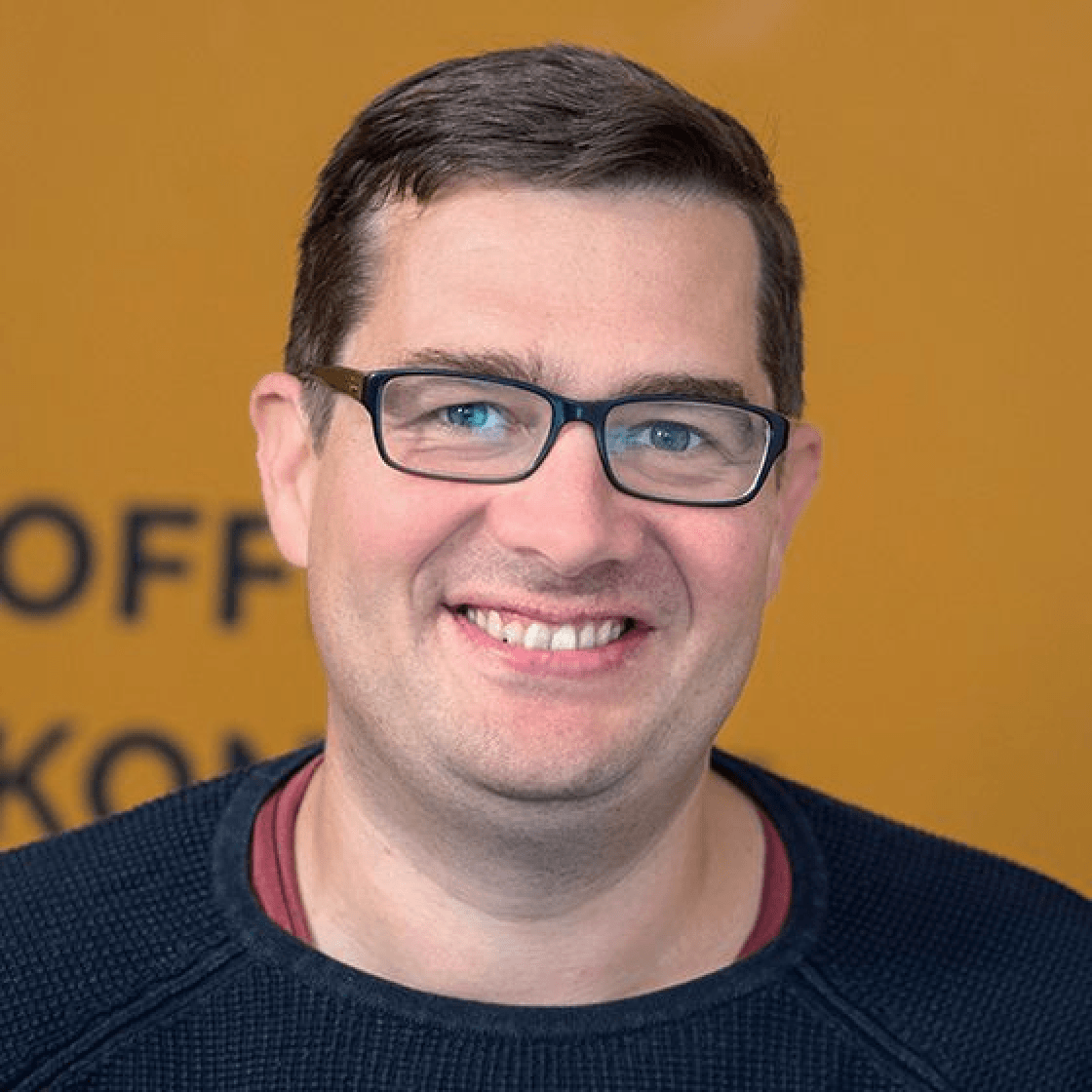 Robert hat dunkelblonde, kurze Haare und eine dunkle Brille. Er lächelt freundlich in die Kamera. 