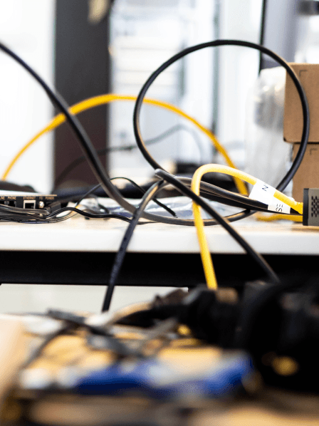 Arbeitsplatz bei MANDARIN mit Netzwerkkabeln, Elektronikkomponenten und technischem Zubehör, symbolisierend eine kreative und technologieorientierte Arbeitsumgebung.