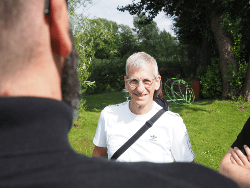 MANDARIN-Mitarbeiter bei einem Outdoor-Event, lächelnd im Gespräch mit Kolleg*innen, umgeben von grüner Natur und Sonnenschein.