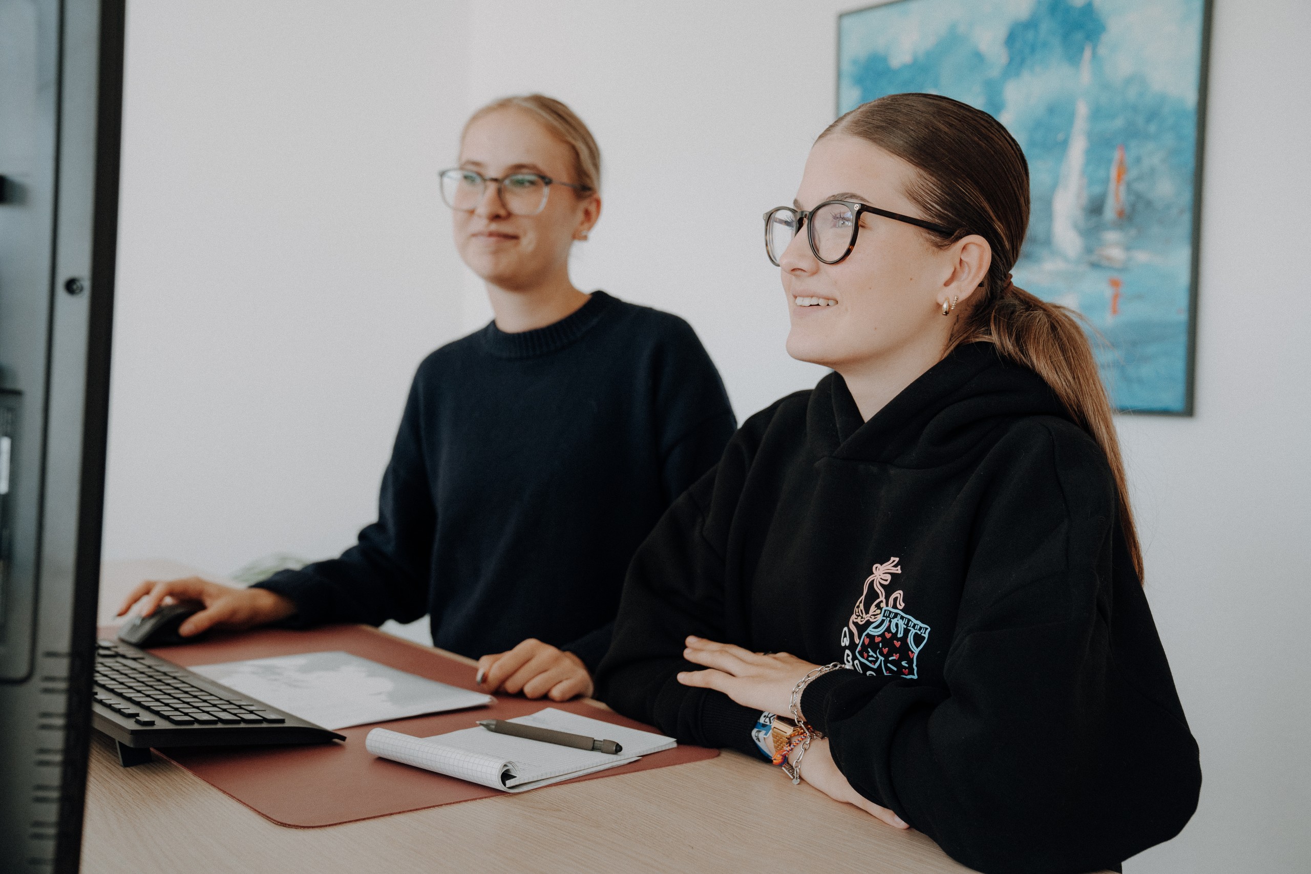 2 Aucon Mitarbeiterinnen vor einem Bildschirm