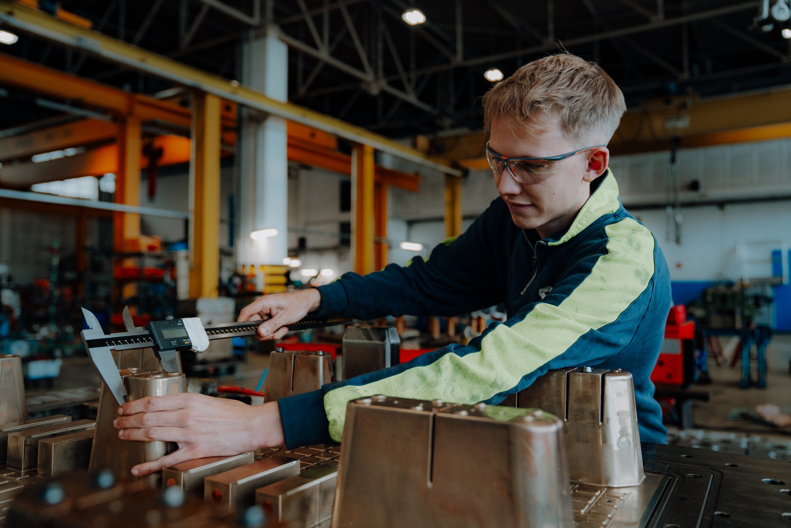 Schöller Alibert Mitarbeiter misst ein Metallteil mit einem digitalen Messschieber in einer Werkstatt