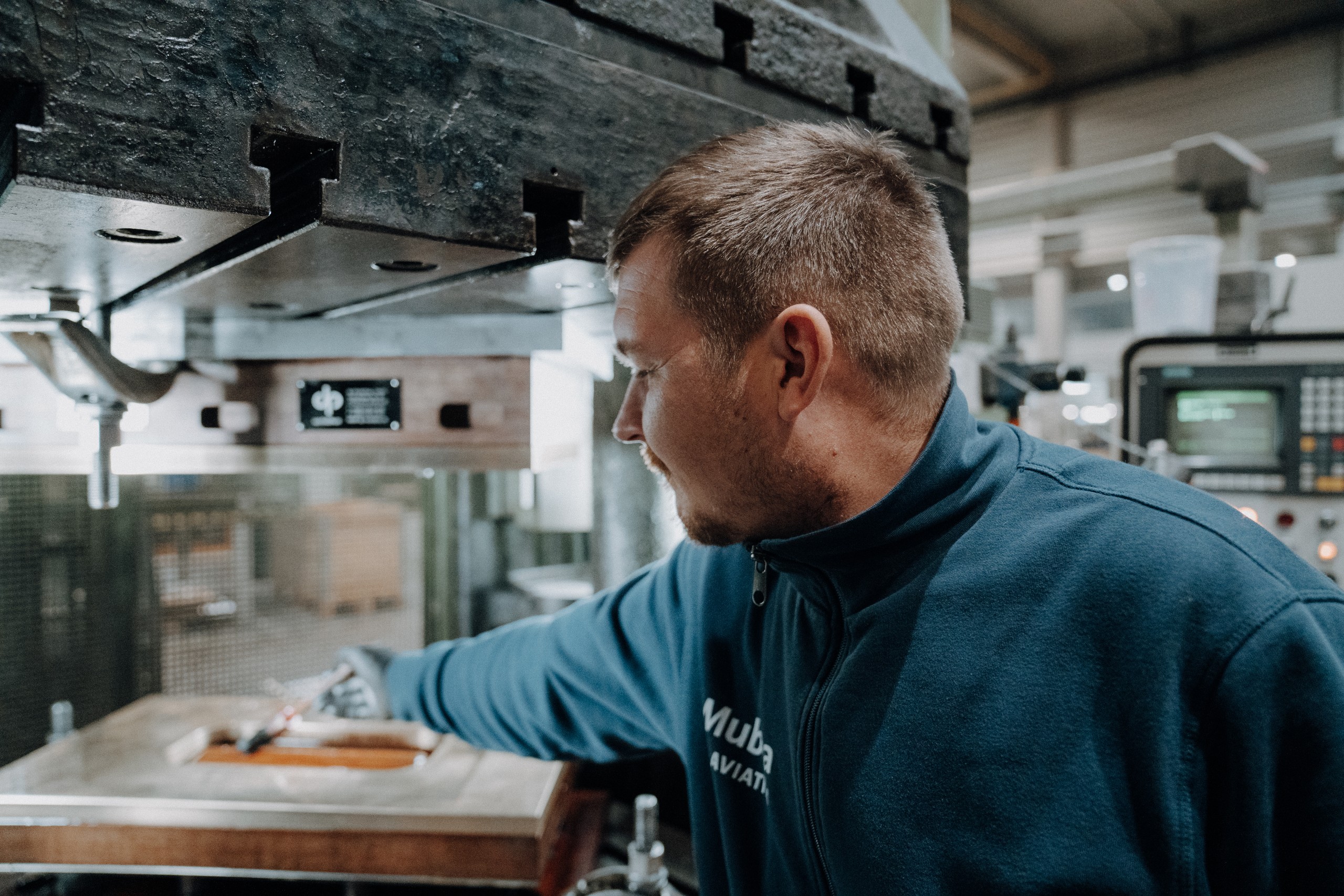 Mubea Mitarbeiter arbeitet an einer Industriemaschine in einer Produktionshalle.