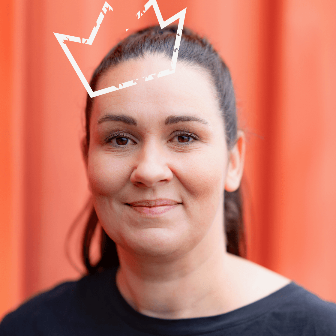 Dieses Porträt zeigt Christina, eine Frau mit dunklem, zurückgebundenem Haar und einem sympathischen Lächeln. Sie trägt ein schwarzes Oberteil, das einen modernen und professionellen Look unterstreicht. Der kräftig orangefarbene Hintergrund setzt einen starken visuellen Akzent und verleiht dem Bild eine energiegeladene, dynamische Ausstrahlung. Ein besonderes Detail: die gezeichnete Krone über ihrem Kopf, die das Bild kreativ und ausdrucksstark macht.