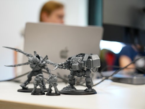 Gaming-Figuren als kreative Deko auf IT-Schreibtisch mit MacBook im Büro.