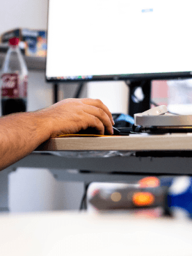 IT-Mitarbeiter arbeitet am Schreibtisch mit Computermaus und Monitor im Büro.
