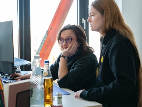 Kolleginnen analysieren Daten am Bildschirm bei gemeinsamer Teamarbeit im Büro.