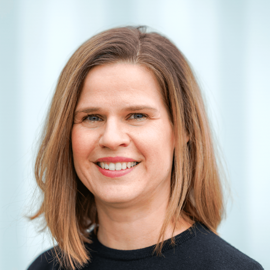 Portrait von Katja, Projektmanagerin bei MANDARIN, lächelnd vor hellem Hintergrund