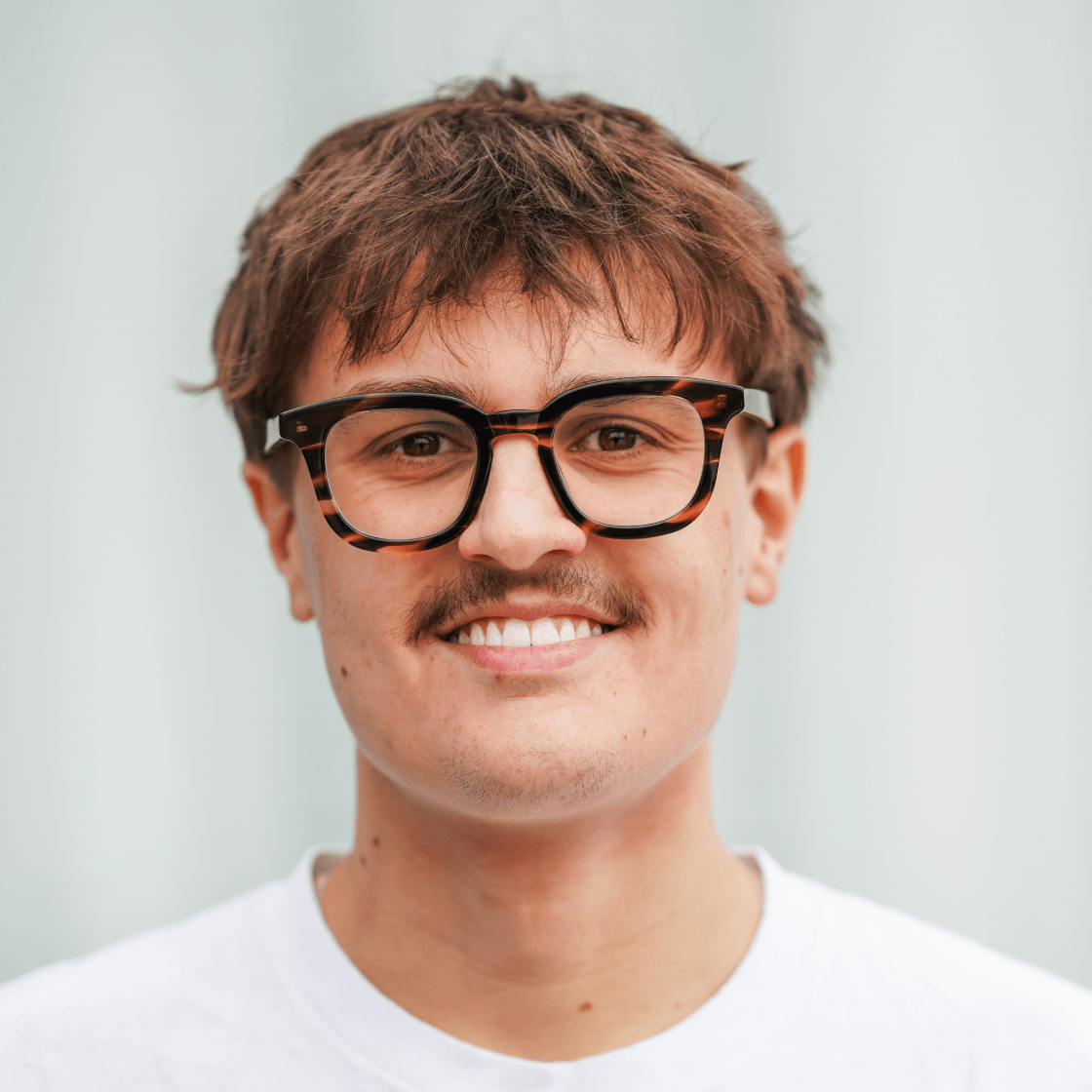 Portrait von Toni, Social Recruiting bei MANDARIN, lächelnd vor hellem Hintergrund