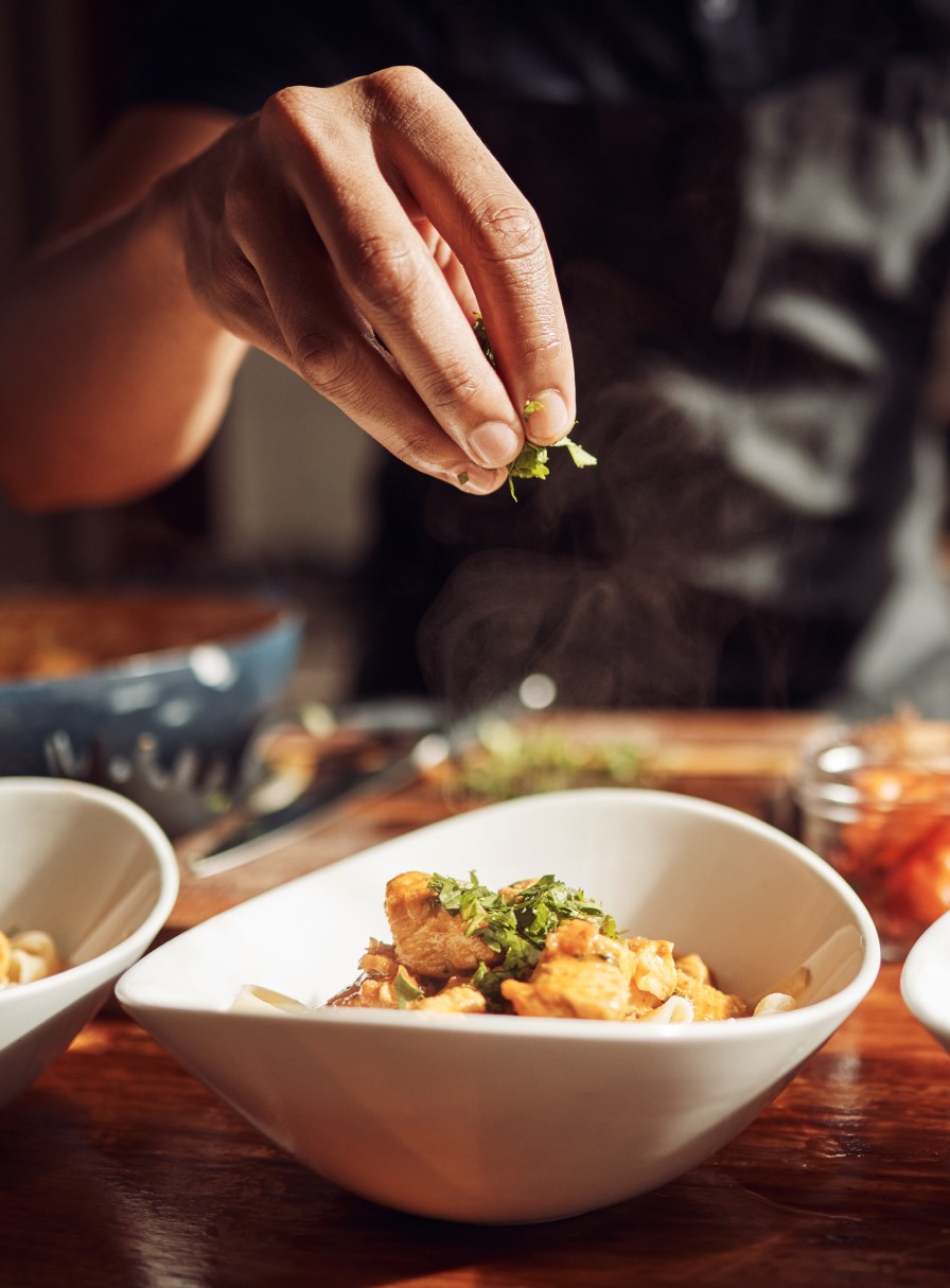 Hand bestreut angerichtetes Essen mit Kräutern 