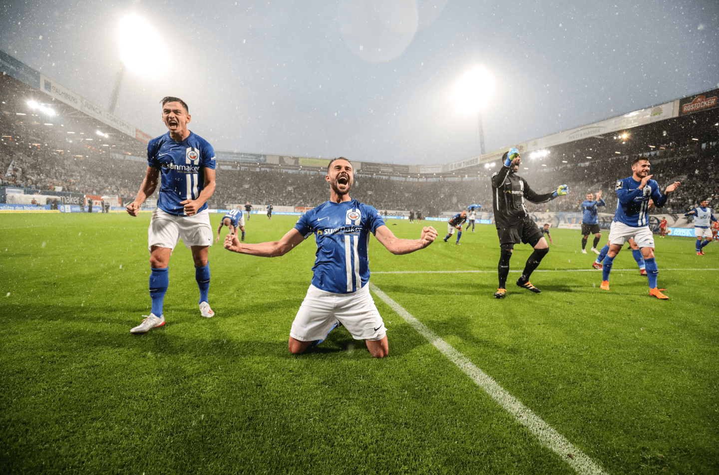 Hansa Fussball Spieler jubeln auf dem Spielfeld nach einem Sieg.