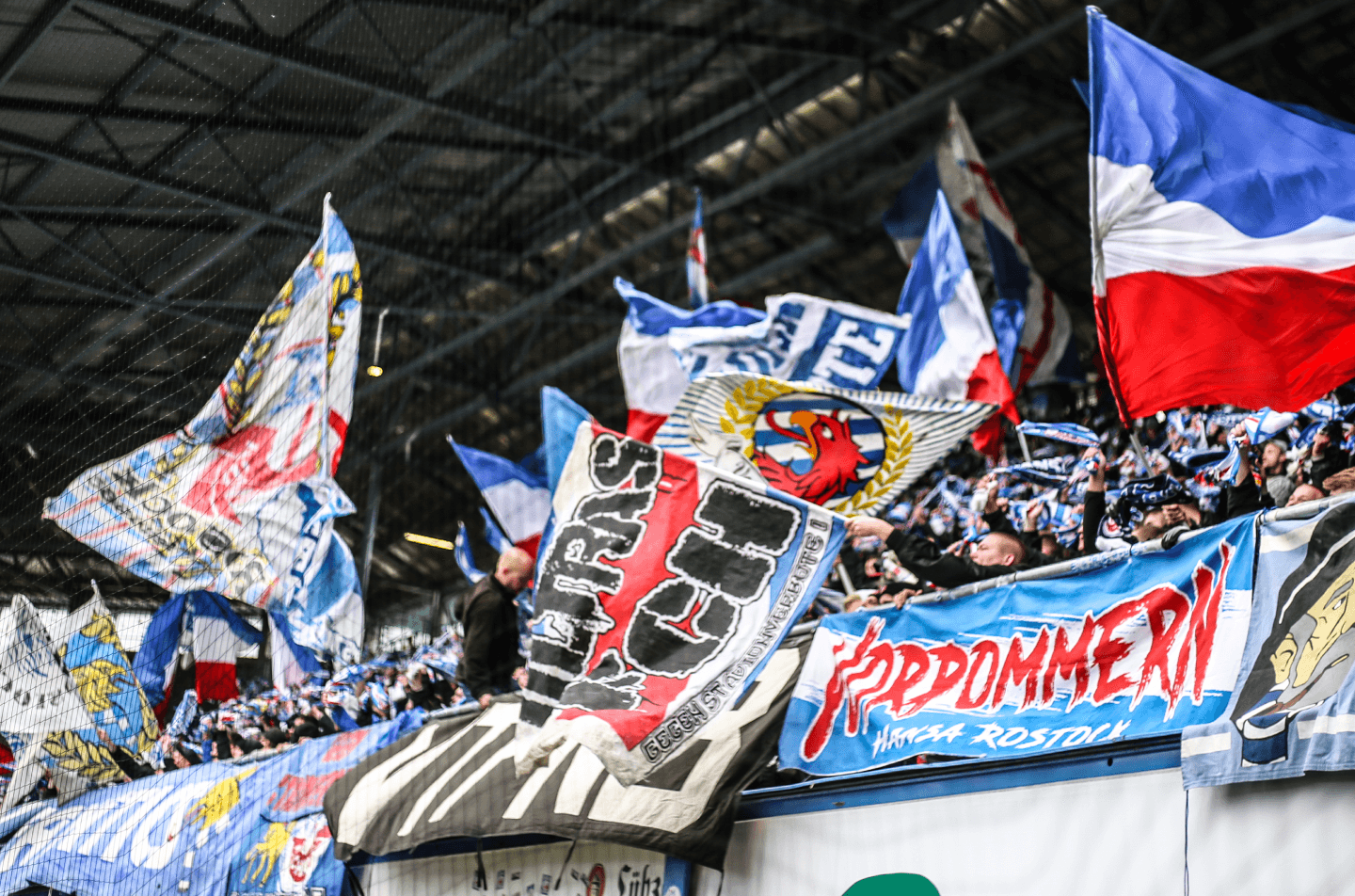 Blick auf eine Fantrebühne vom F.C. Hansa Rostock mit vielen Fahnen.