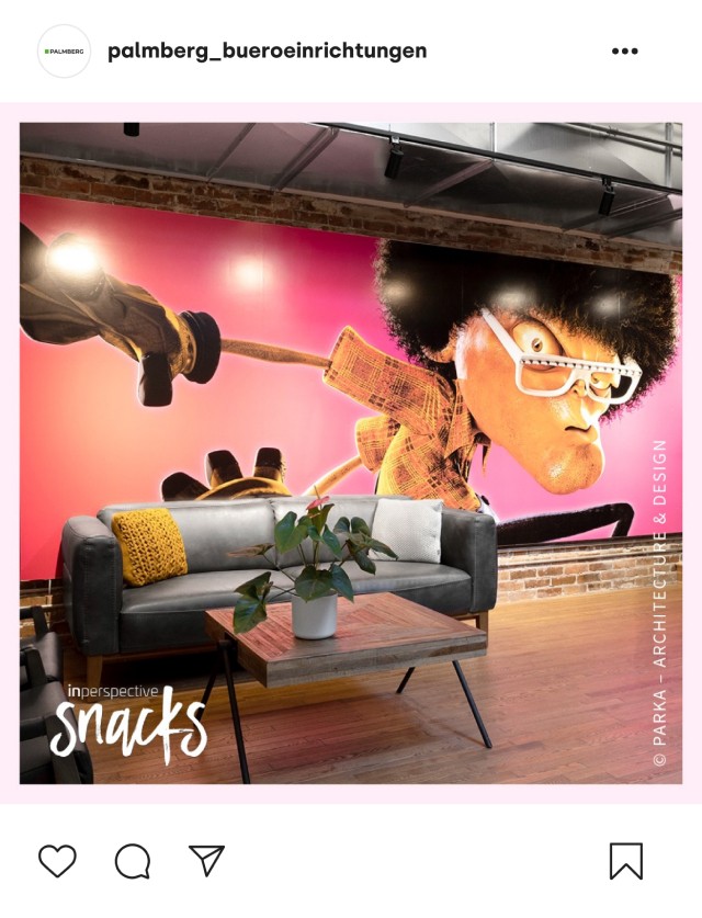 nstagram-Beitrag von palmberg_bueroeinrichtungen mit einem modernen Bürobereich, einer grauen Couch und einer auffälligen Wandmalerei von einem Charakter mit Afro und Brille.