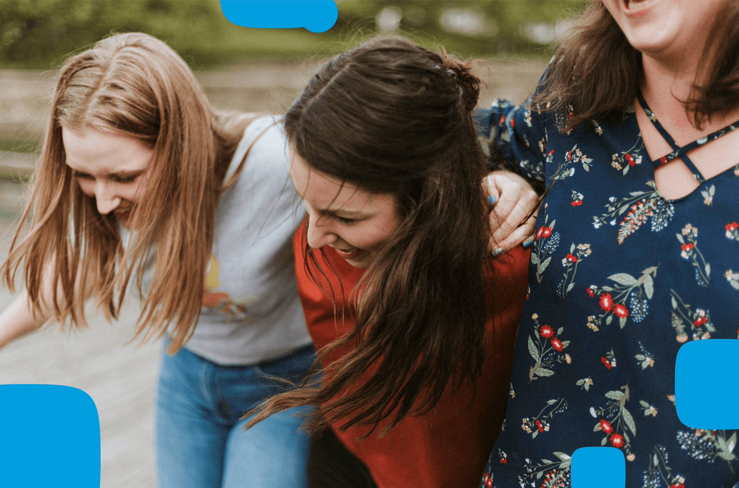 Drei lachende Frauen in enger Umarmung genießen einen fröhlichen Moment im Freien. Die Szene strahlt Gemeinschaft, Freude und Zusammenhalt aus, mit einem natürlichen Hintergrund und lebendigen Farben.