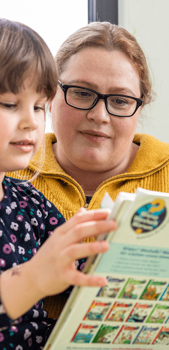 Mitarbeiterin des Internationalen Bundes liest gemeinsam mit einem Kind – individuelle Förderung und frühkindliche Bildung in der Kita oder sozialen Einrichtung.