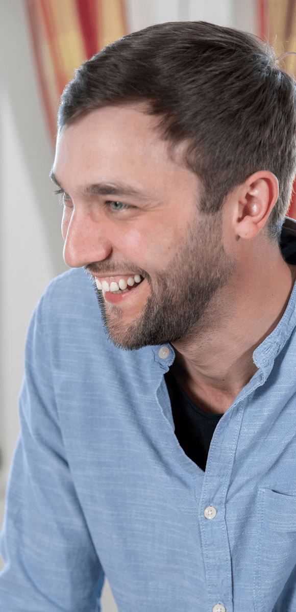 Junger Mitarbeiter des Internationalen Bundes lacht während eines Gesprächs – positive Arbeitsatmosphäre und Teamgeist im sozialen Bereich.