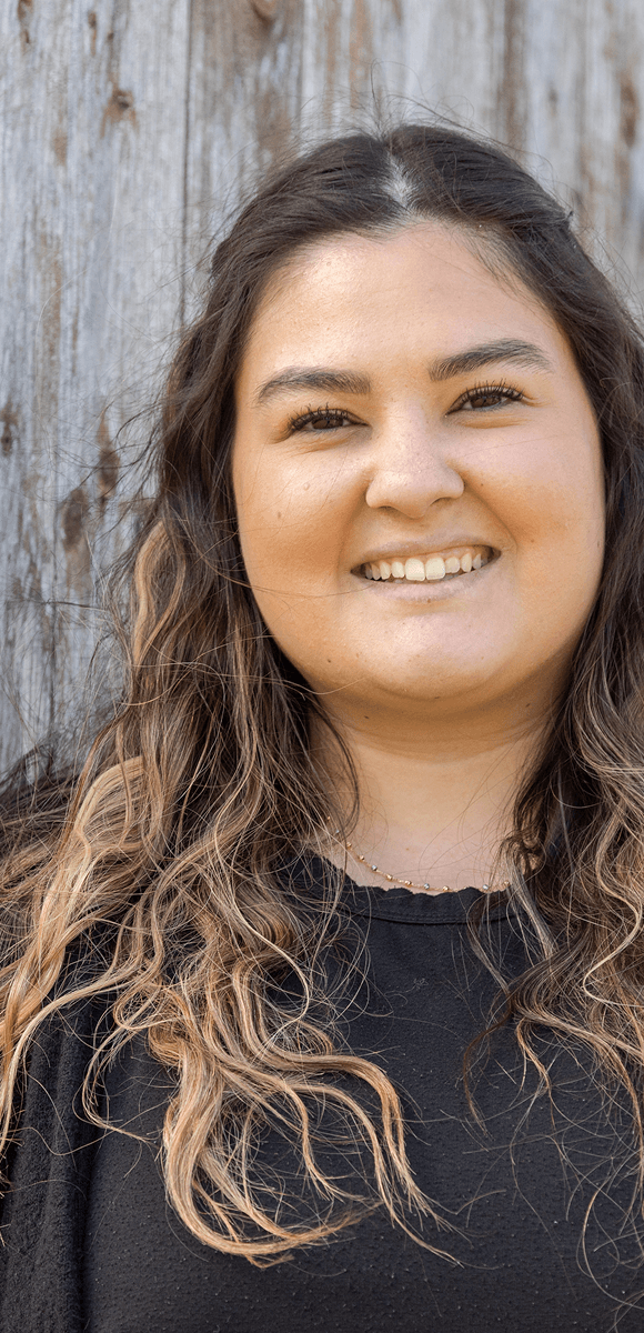 Junge Mitarbeiterin des Internationalen Bundes lächelt in die Kamera – authentisch, engagiert und motiviert für eine sinnstiftende Karriere im sozialen Bereich.