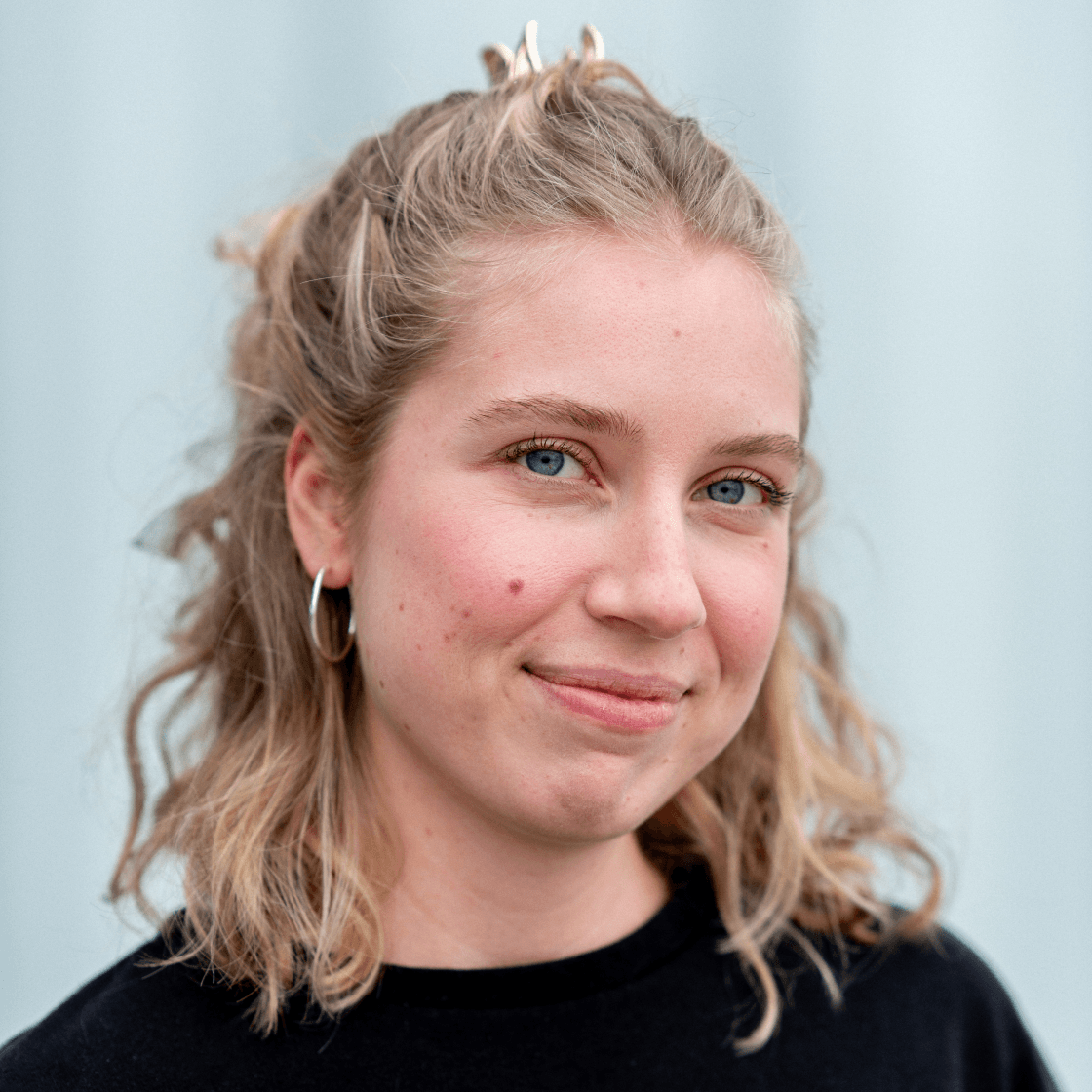 Portrait von Celina, Designerin bei MANDARIN, lächelnd vor hellem Hintergrund