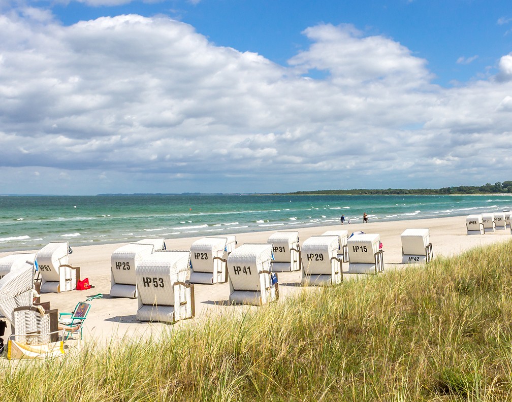 Ostseestrand mit Meer, Strandkörben, Strandhafer, blauer Himmel, leicht bewölkt