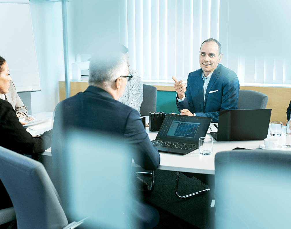 Modernes Business-Meeting bei MD Nord: Team diskutiert Strategien im Konferenzraum mit Laptops und Unterlagen, professionelle Zusammenarbeit im Büro.