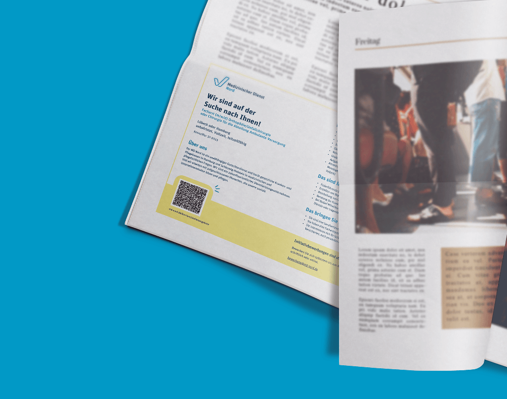 Nahaufnahme einer Stellenanzeige des MD Nord in einer Tageszeitung, die aufgeschlagen auf einer blauen Farbfläche liegt.