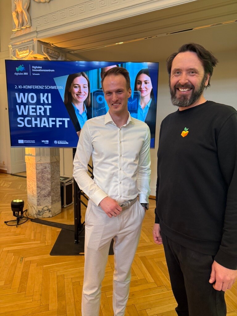 Gérard Kühnel und Alexander Balow bei der KI-Konferenz im Digitalen Innovationszentrum (DIZ) in Schwerin, vor Präsentationsscreen zum Thema „Wo KI Wert schafft“
