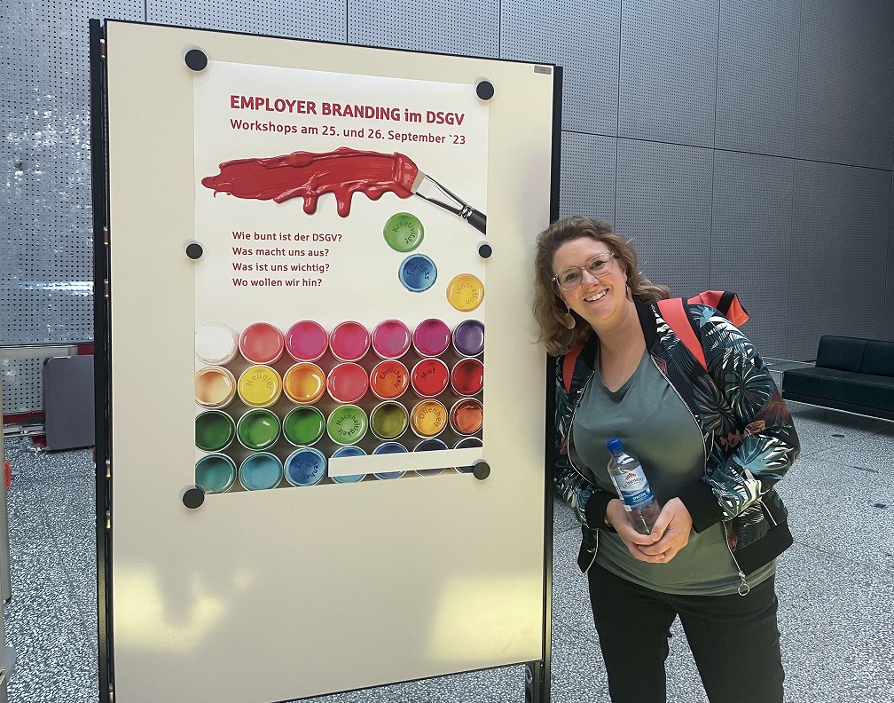 Teilnehmerin des Workshops steht vor einem Plakat am Whitboard.