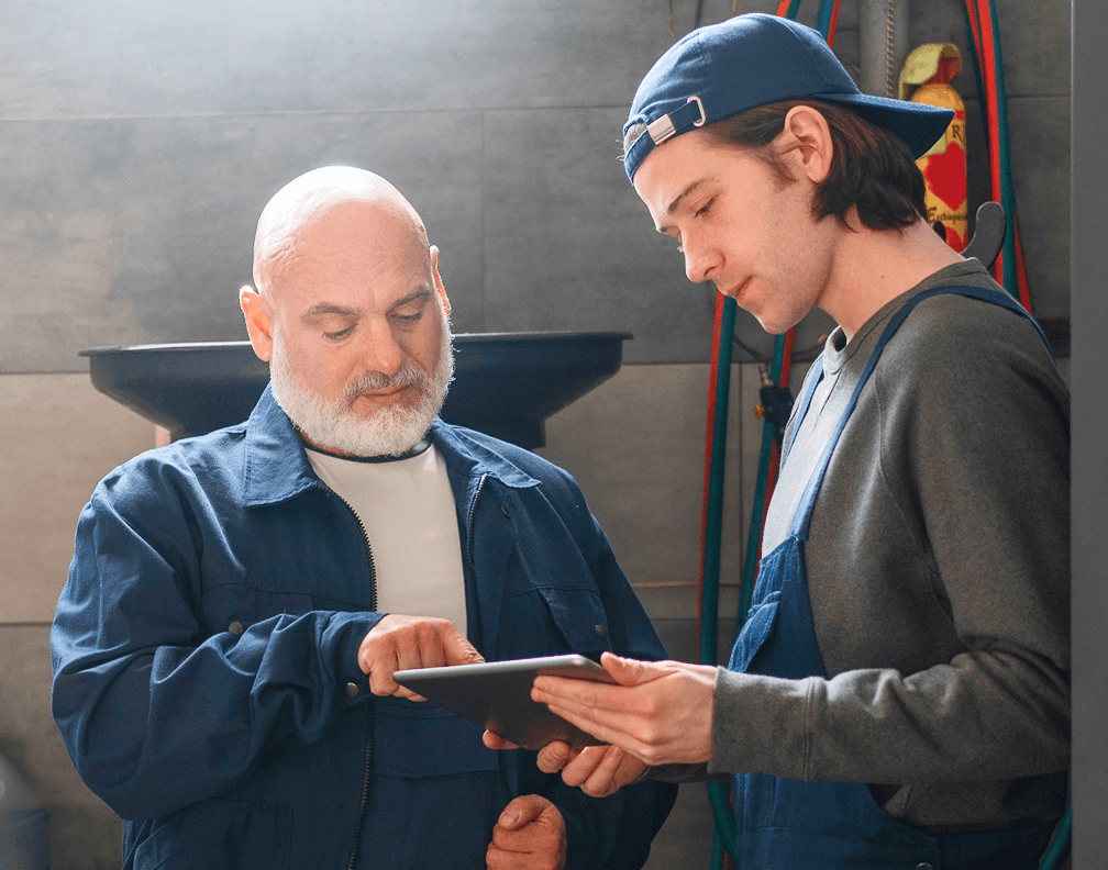 Zwei technische Mitarbeiter eines Unternehmens beraten sich am Tablet.